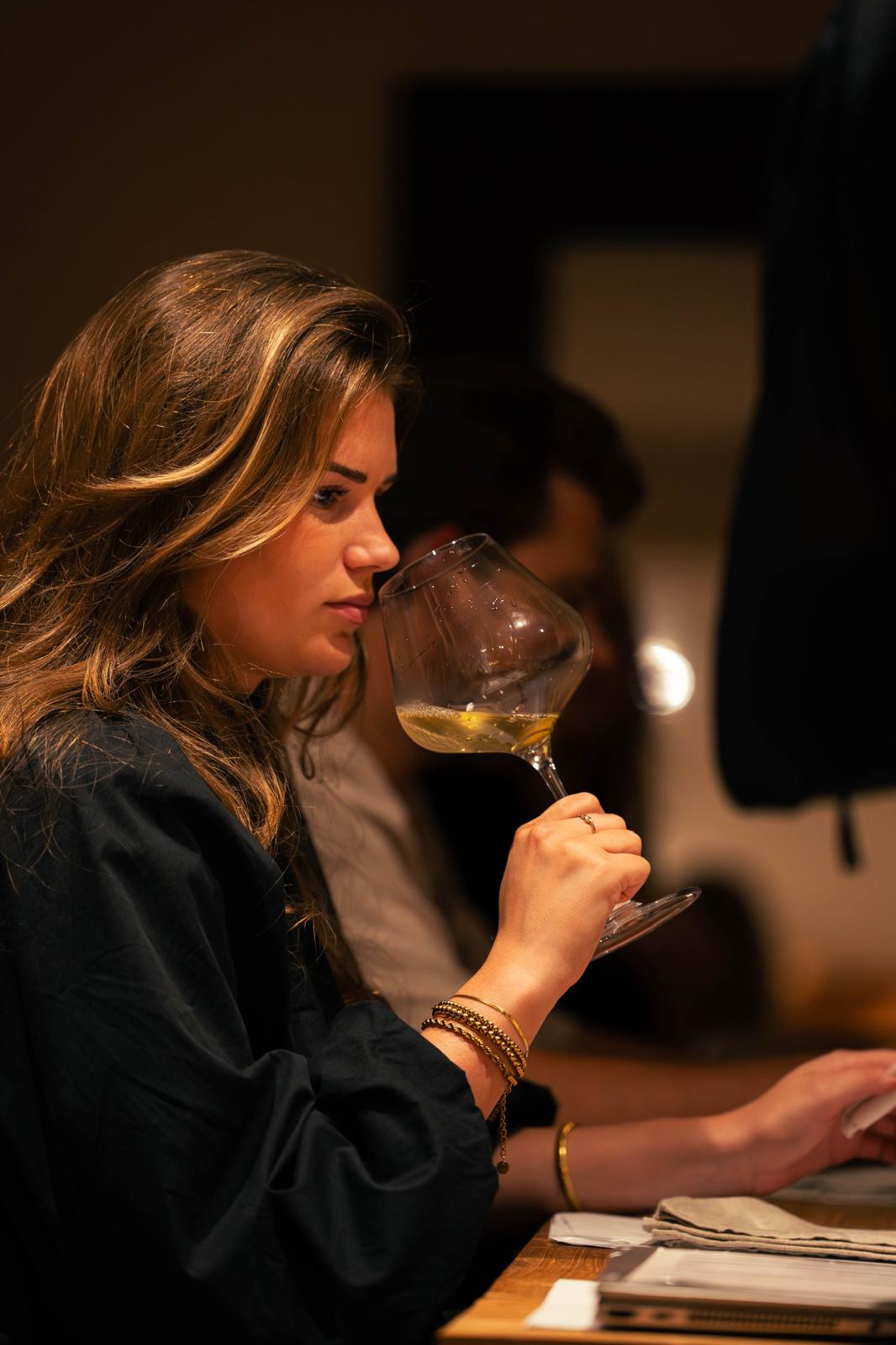 Een gast ruikt geconcentreerd aan een glas witte wijn
