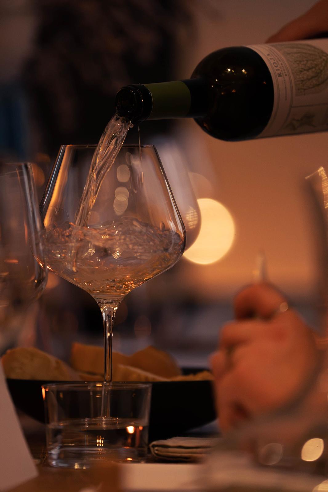 Witte wijn wordt bij kaarslicht in een glas geschonken