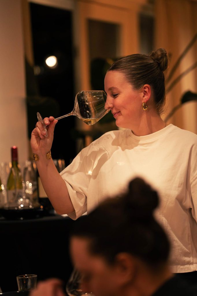 De sommelier ruikt glimlachend aan een glas witte wijn